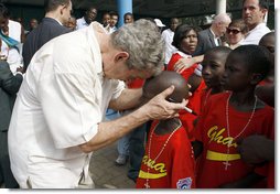 President George W. Bush embraces a young boy after a tee ball game Wednesday, Feb. 20, 2008, at the Ghana International School in Accra, Ghana. White House photo by Eric Draper