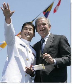 President George W. Bush holds a coin presented to him by U.S. Coast Guard graduate Daniel Kyung-Hyun Han, after President Bush presented him with his commission Wednesday, May 23, 2007, at the U.S. Coast Guard Academy commencement in New London, Conn. White House photo by Joyce Boghosian