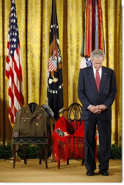 President George W. Bush bows his head during a prayer Monday, March 3, 2008 in the East Room of the White House, standing before two chairs in honor of U.S. Army Master Sgt. Woodrow Wilson Keeble, left, and his wife, Bloosom, moments before presenting members of the Keeble family with the Medal of Honor, posthumously, in honor of Master Sgt. Keeble’s gallantry during his service in the Korean War. Keeble is the first full-blooded Sioux Indian to receive the Medal of Honor. White House photo by Eric Draper